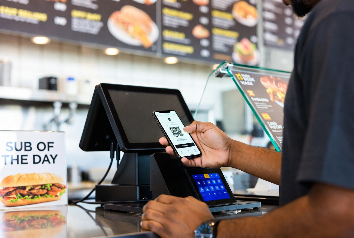 Customer scanning QR code on phone to redeem loyalty points or gift card at restaurant counter using Level POS system